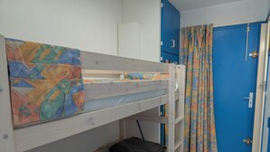 A bunk bed with colorful bedding, a blue door, and a curtain. - Sol-y-Days Floralies 2, Studio with terrace and swimming pool (Le Grau-du-Roi)