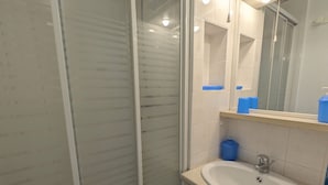 A bathroom with a glass shower enclosure, a white sink, and a mirror above it. - Sol-y-Days Floralies 2, Studio with terrace and swimming pool (Le Grau-du-Roi)