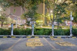 A parking area with marked spaces, trees, and a building in the background. - Korla Ronghui Yi Hotel (Xiangli Avenue Food Street Branch) (Korla)