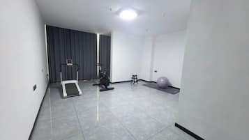 A room with a treadmill, exercise ball, and weights.