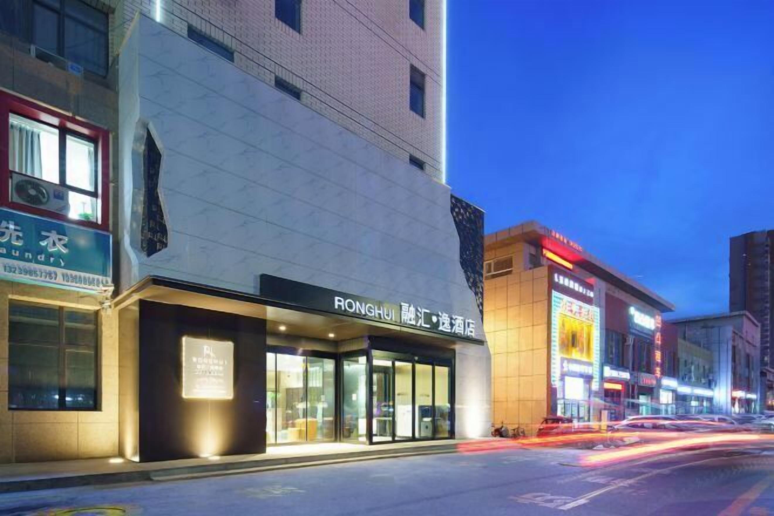 A hotel with a modern facade, large glass windows, and a sign indicating it is a RONGHUI hotel.