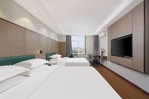 Habitación de hotel con dos camas, televisión, una mesita y ventana con vistas a la ciudad.