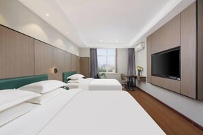A hotel room with two beds, a TV, a small table, and a window with a city view.