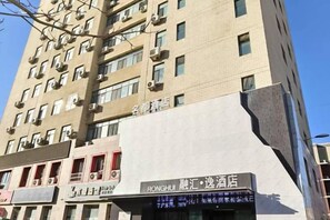 A multi-story building with a modern architectural design, featuring a prominent signage for a hotel named 'RONGHUI' and a restaurant named 'RONGHUI'. - Korla Ronghui Yi Hotel (Xiangli Avenue Food Street Branch) (Korla)
