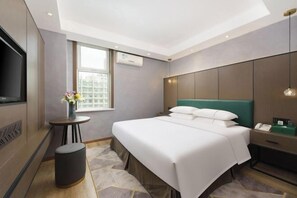 Une chambre d’hôtel avec un lit, une table de chevet, une lampe et un téléviseur.