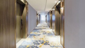 A long, narrow hallway with a patterned floor and modern elevator doors on either side. - Korla Ronghui Yi Hotel (Xiangli Avenue Food Street Branch) (Korla)