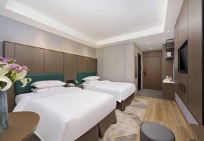 Une chambre d’hôtel avec deux lits, un bureau, une chaise, une télévision et une salle de bain.