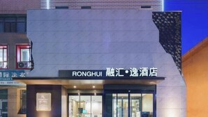 A hotel with a modern facade, featuring a sign that reads "RONGHUI RONGHUI HOTEL". - Korla Ronghui Yi Hotel (Xiangli Avenue Food Street Branch) (Korla)