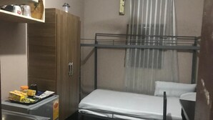A compact room with a bunk bed, a small kitchenette, and a wooden wardrobe.