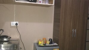 A compact kitchen with a small refrigerator, a sink, and a wooden cabinet.