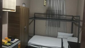 A bunk bed with a mosquito net, a wooden wardrobe, and a ceiling fan.