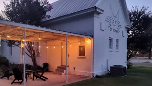 A white building with a covered outdoor area, outdoor seating, and a sign reading "St. Chris." - St. Chris - Graham, TX (Graham)