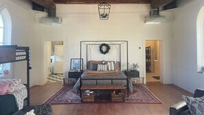 A spacious bedroom with a large bed, a ceiling fan, and a view of the kitchen. - St. Chris - Graham, TX (Graham)