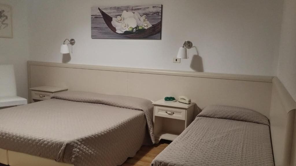 Une chambre d’hôtel avec deux lits, une table de chevet, une lampe et un tableau accroché au mur.