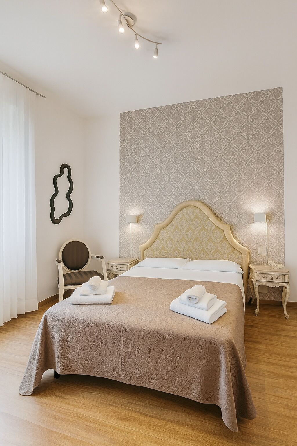 Ein ordentlich gemachtes Bett mit einem gemusterten Überwurf, zwei Nachttischlampen, ein Sessel und eine Wand mit einem geometrischen Muster.