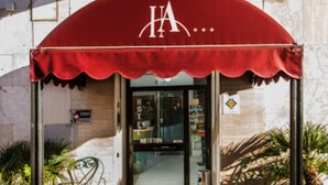 A hotel entrance with a red awning and a sign above it. - HOTEL ARISTON (Piombino)