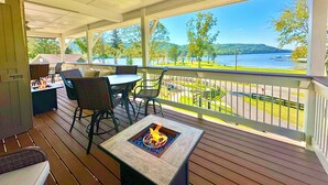 Terraza cubierta al aire libre con una chimenea, asientos y vistas a un lago.
