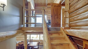 Un interior de fusta amb una escala, una zona de menjador i una gran porta de fusta.