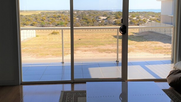 A room with a sliding glass door leading to a balcony with a view of a rural landscape and a body of water.