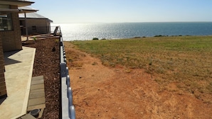 Una propiedad costera con un sendero de tierra que lleva a un área verde con vista al mar.