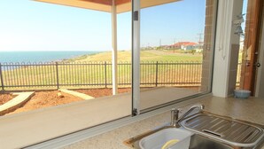 Cocina con vista al mar, un lavabo y una ventana con reja de metal en el exterior.