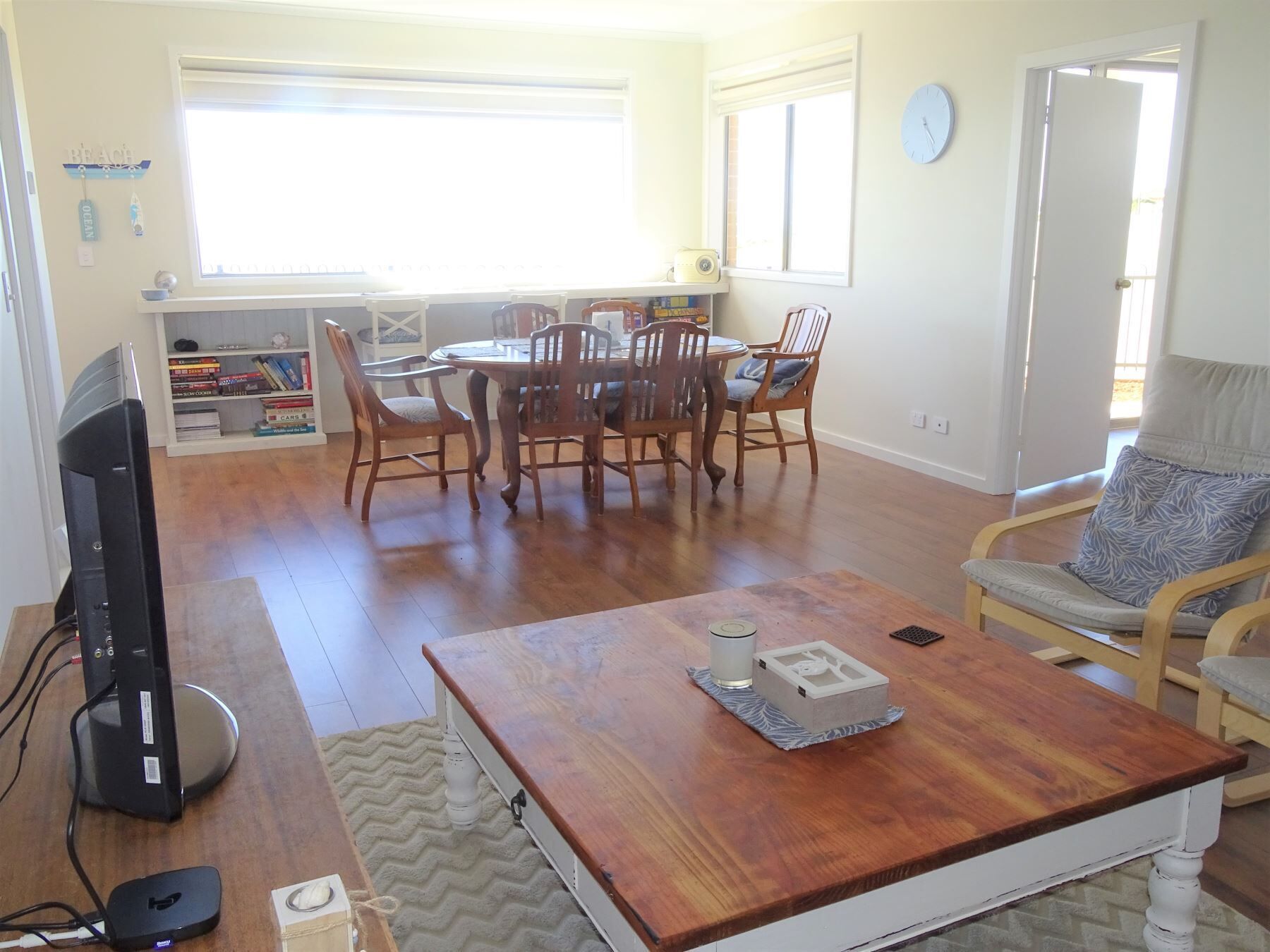 Una sala de estar con una mesa de centro de madera, un televisor y un comedor con una mesa y sillas.
