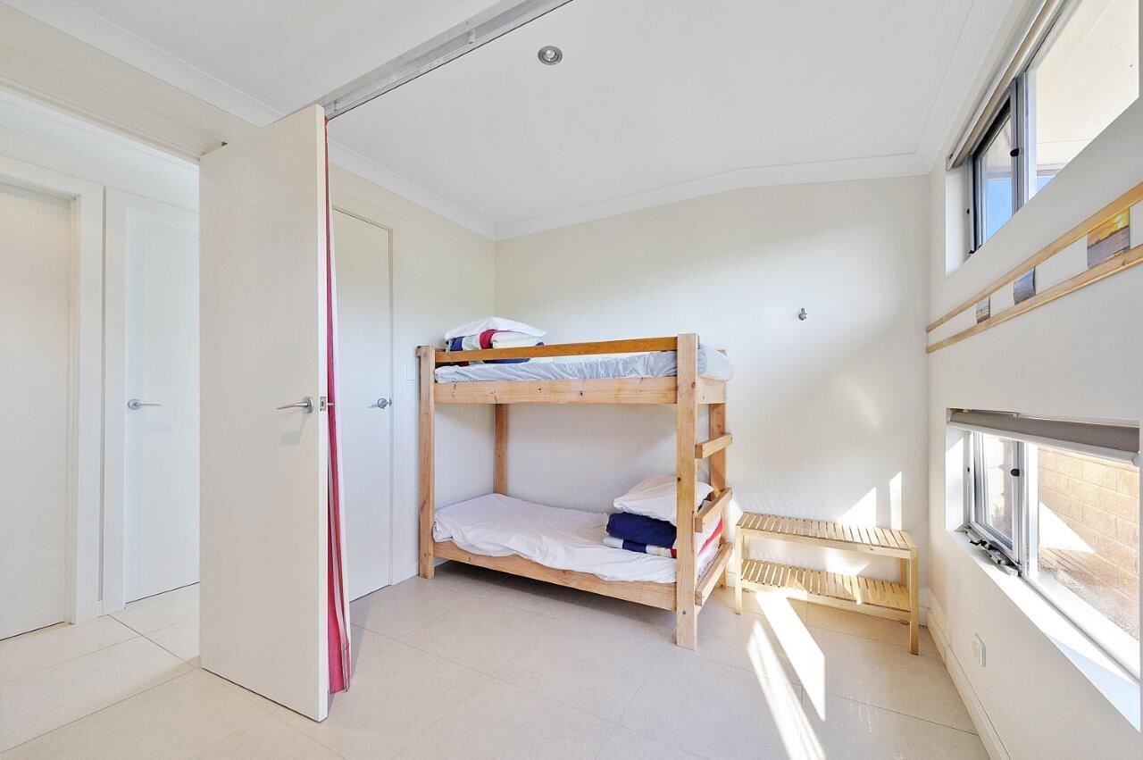 A small, bright room with a bunk bed, a door, and a window.