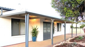 A modern house with a covered porch, a potted plant, and a well-maintained garden.