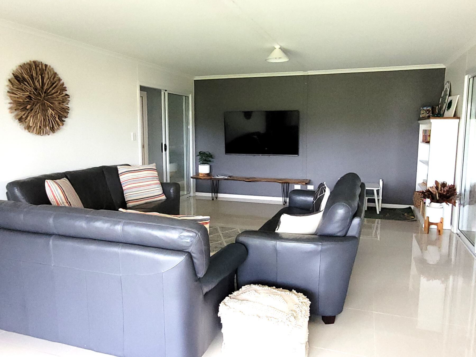 A modern living room with a sofa set, a coffee table, and a flat-screen TV mounted on the wall.