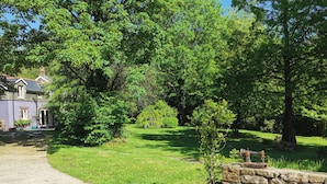 A house with a stone wall and a paved driveway. - Countryside Cottage Retreat at Ty'r Cwm Farm (Ammanford)