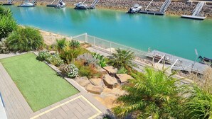 A marina with boats docked, a landscaped area with grass and plants, and a view of houses in the background. - Happy Days, Wallaroo (Wallaroo)