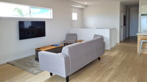 A modern living room with a grey sofa, a small wooden table, and a TV mounted on the wall. - Beachfront Beauty, Moonta Bay (Moonta Bay)