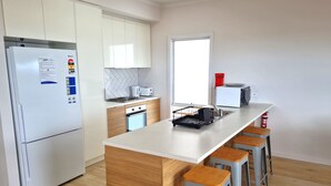 A modern kitchen with white cabinets, a built-in oven, a refrigerator, and a large window. - Beachfront Beauty, Moonta Bay (Moonta Bay)