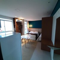 Habitación de hotel pequeña con cama, una mesita y una silla. Una ventana ofrece luz natural y vistas al exterior.
