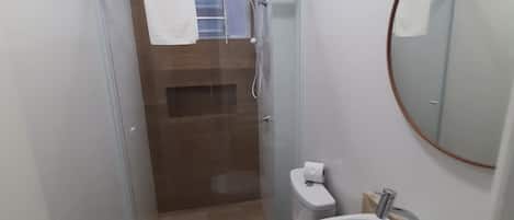 Un baño pequeño con inodoro, lavamanos y ducha.