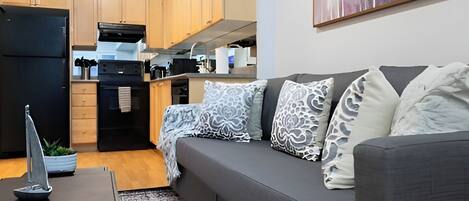 A modern living room with a grey sofa, a small table, and a decorative sailboat model.