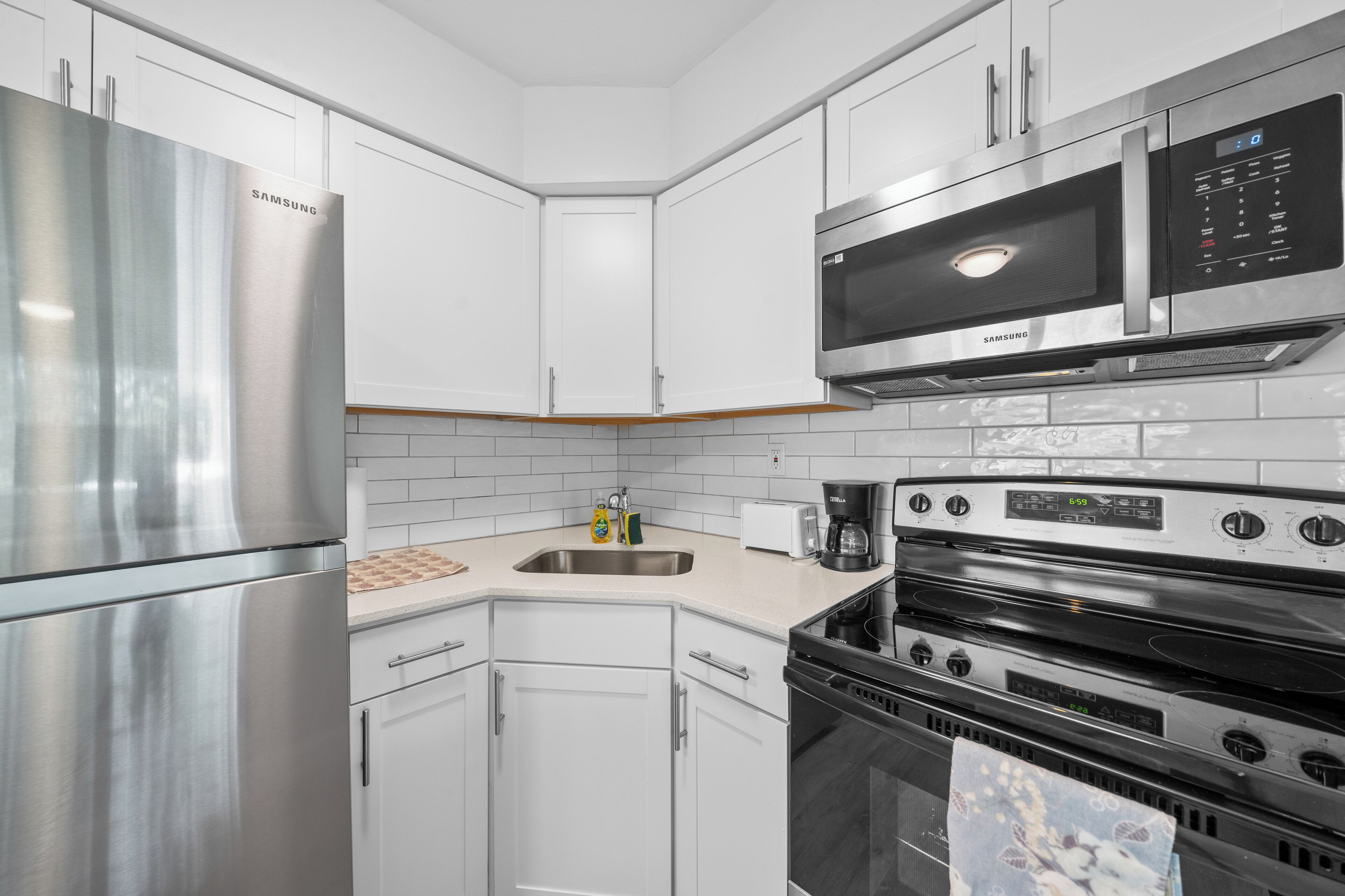 A modern kitchen with stainless steel appliances, white cabinetry, and a built-in microwave.