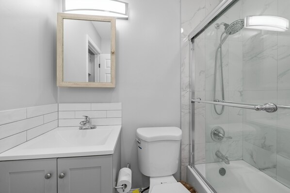 A modern bathroom with a white sink, a toilet, and a glass-enclosed shower area. - Riverbend by Lowkl (Fort Lauderdale)