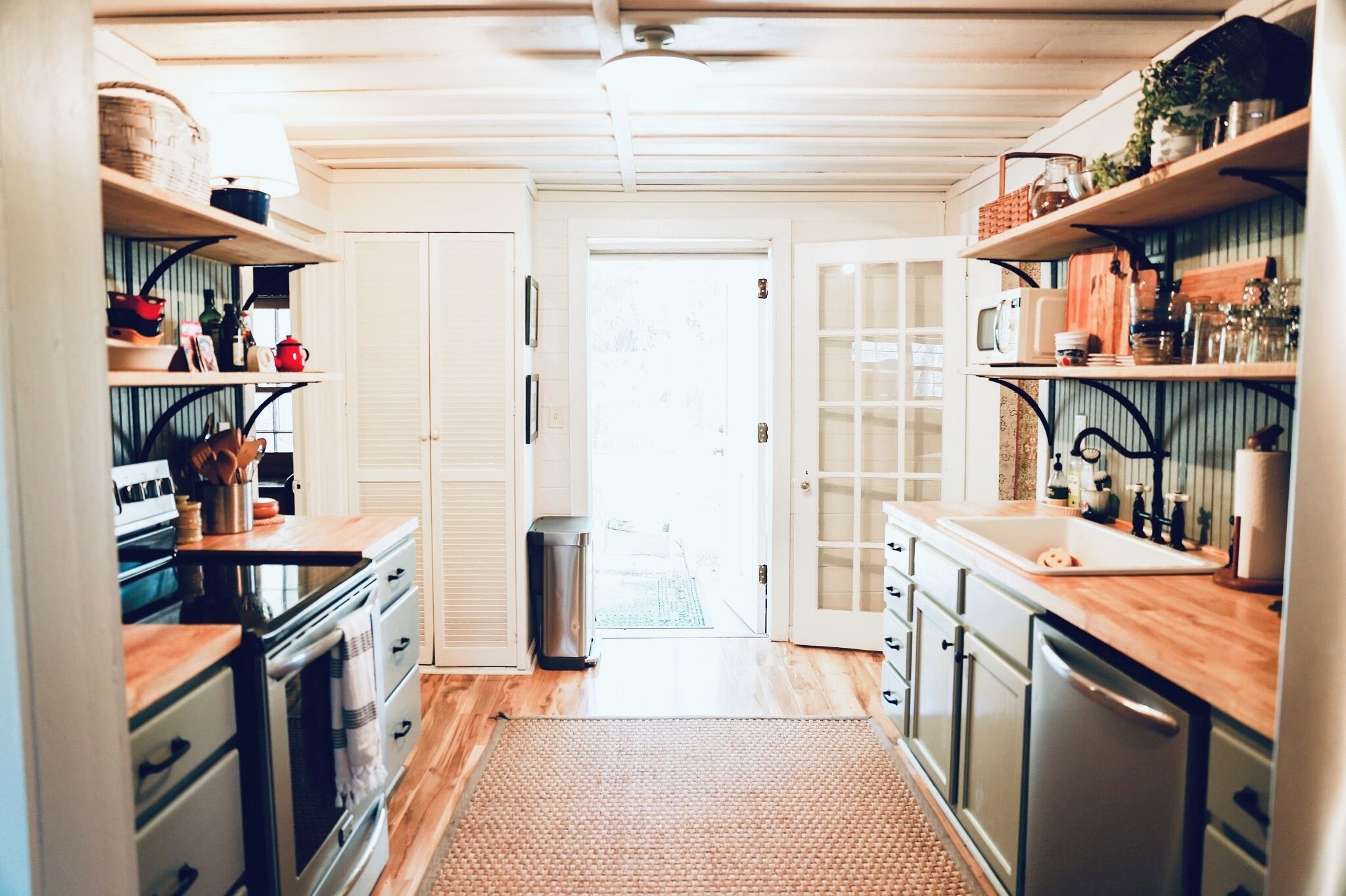 A kitchen with wooden cabinets, a stainless steel stove, and a trash can.