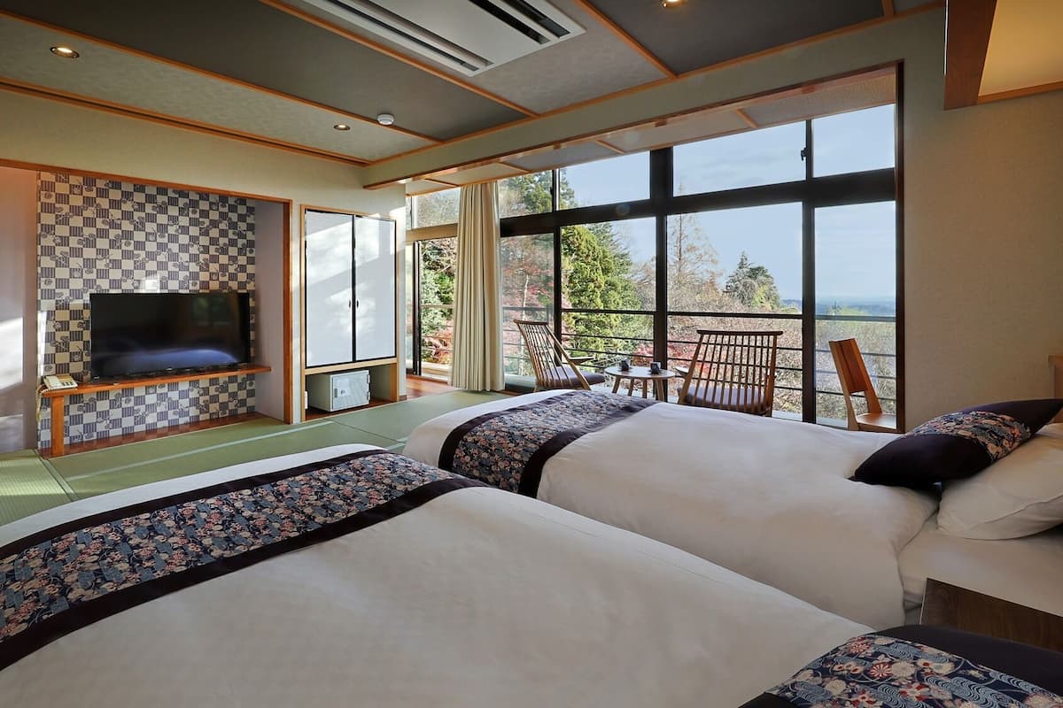 A hotel room with two beds, a TV, and a balcony with a view.