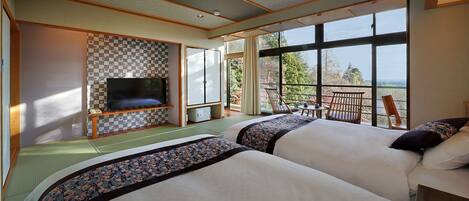 A hotel room with two beds, a TV, and a balcony with a view.