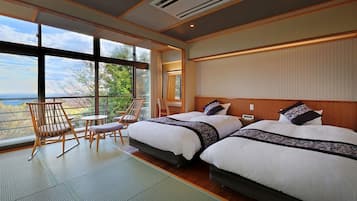 A hotel room with two beds, a balcony with a view, and a seating area with chairs and a table.