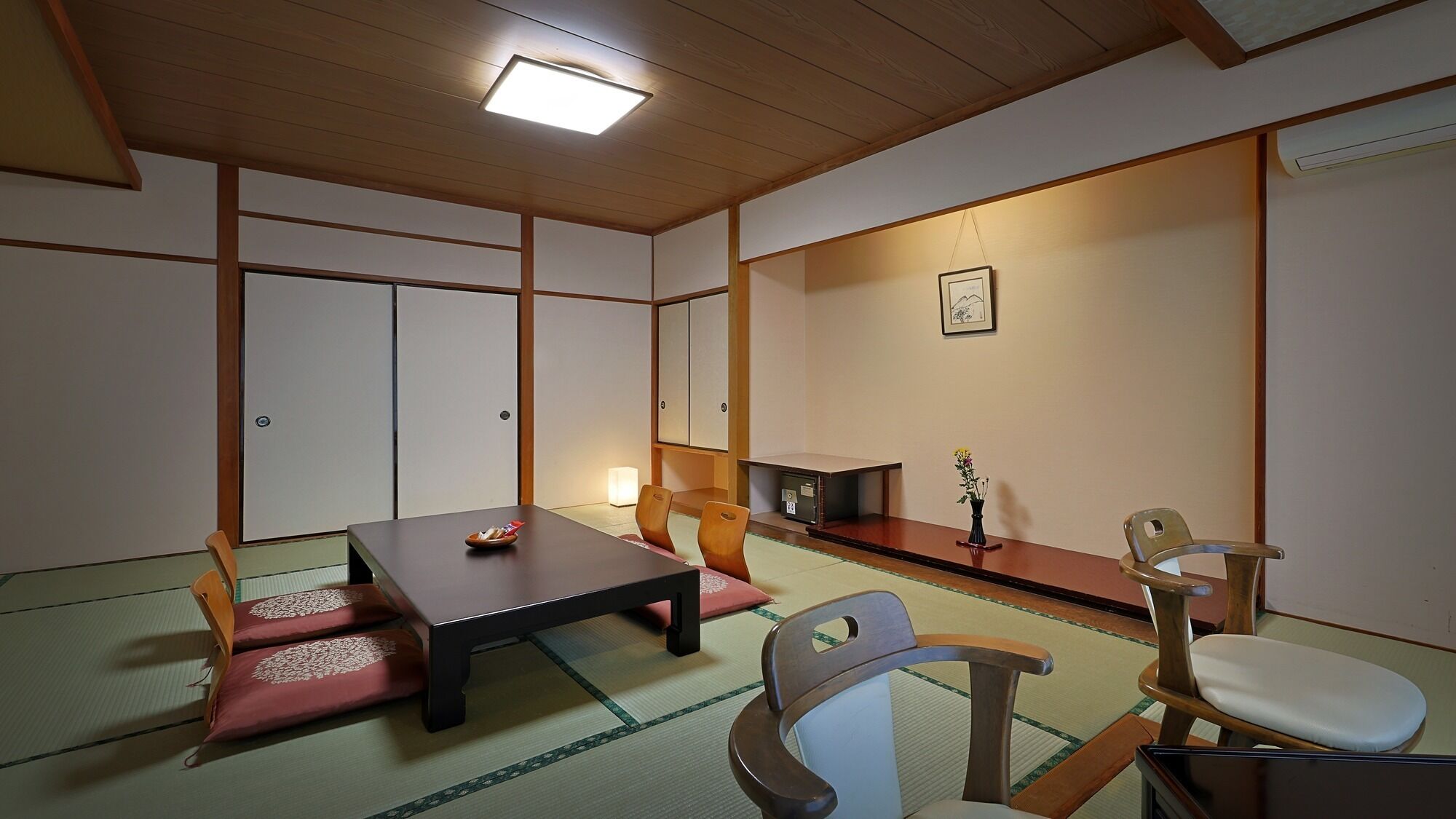 Une pièce de style japonais traditionnel, avec un sol recouvert de tatamis, une table basse et des chaises en bois.