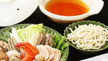 A variety of dishes including noodles, seafood, and vegetables, served on a black table.