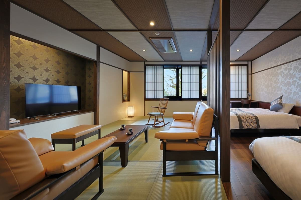 A hotel room with a television, sofa, and two beds.