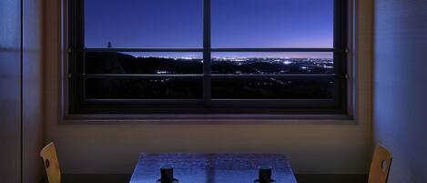 Une pièce dotée d’une grande fenêtre donnant sur une vue panoramique de la ville la nuit.