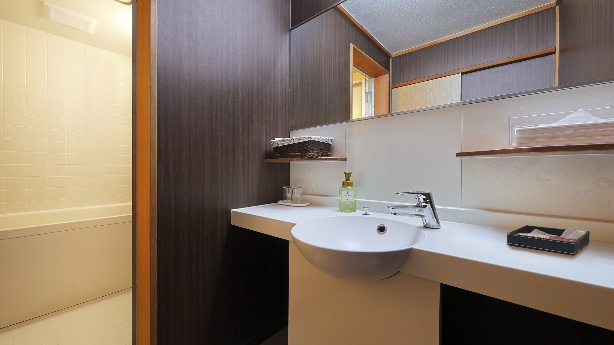 Un baño moderno con un lavamanos blanco, un espejo y un estante de madera sobre el espejo.