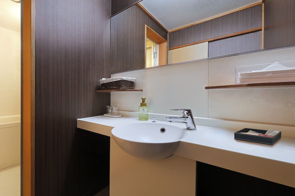 Un baño moderno con un lavamanos blanco, un espejo y un estante de madera sobre el espejo.