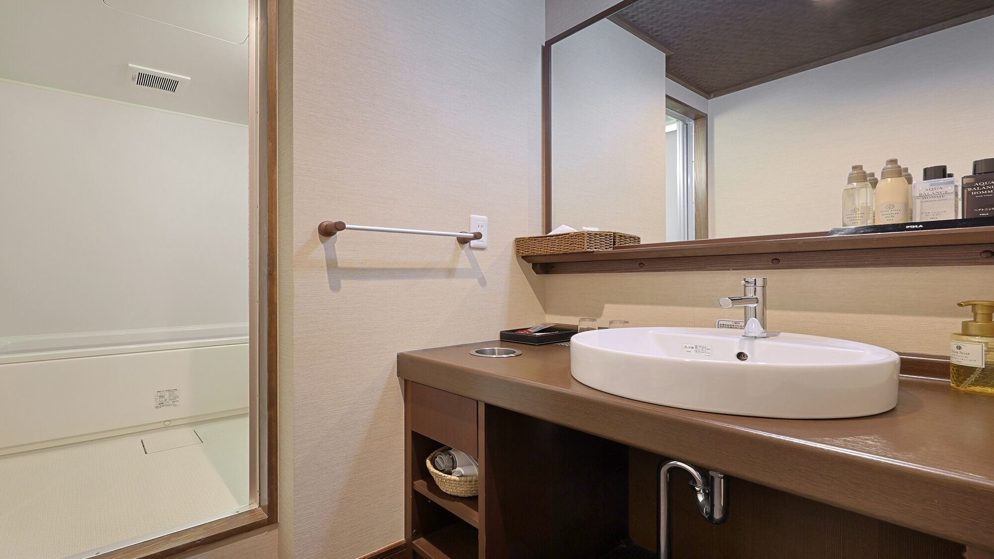 A bathroom with a white sink, a mirror, and toiletries on the counter.