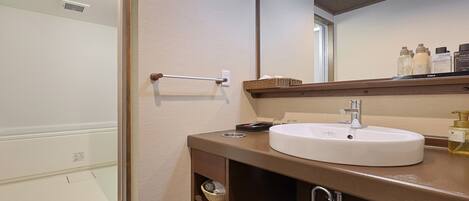 A bathroom with a white sink, a mirror, and toiletries on the counter.